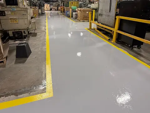 Industrial facility floor coated in grey epoxy with yellow safety lines
