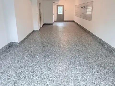 Long garage with white walls and a grey flake epoxy floor that curves up into a grey base along the walls