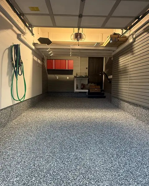 Single garage with slatwall, red cabinets and a flake epoxy floor