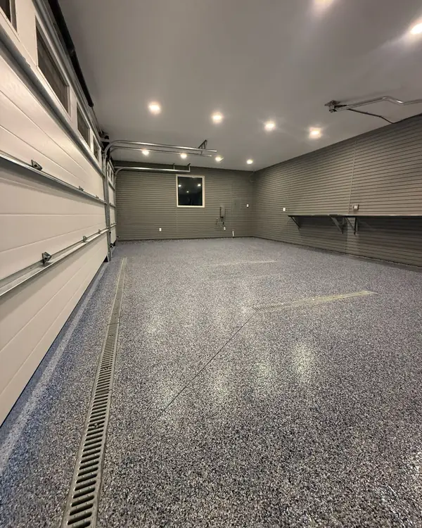 Long two-car garage with a grey flake epoxy floor and slatwall panels on the walls